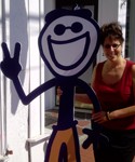 A woman posing next to a smiling cartoon character.