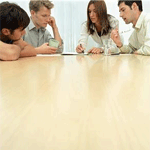 A group of people sitting around a wooden table.