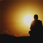A silhouette of a man sitting in front of a sunset.