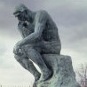 A statue of the thinker sitting on a bench.