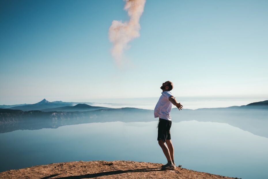 A man standing on top of a mountain with smoke coming out of his mouth.